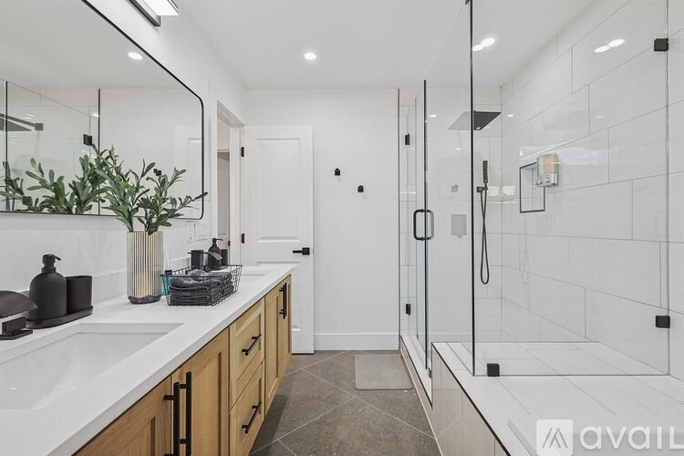 A bathroom with a sink, mirror, and shower.