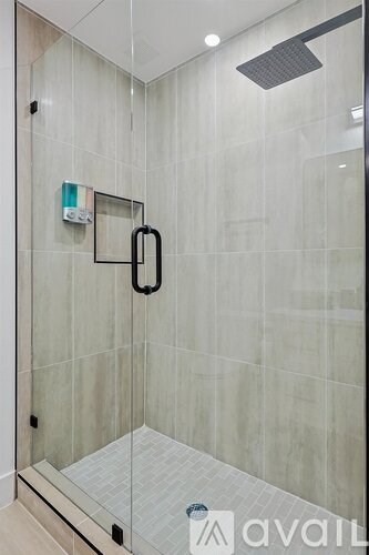 A glass shower stall with a black handle and a glass door.