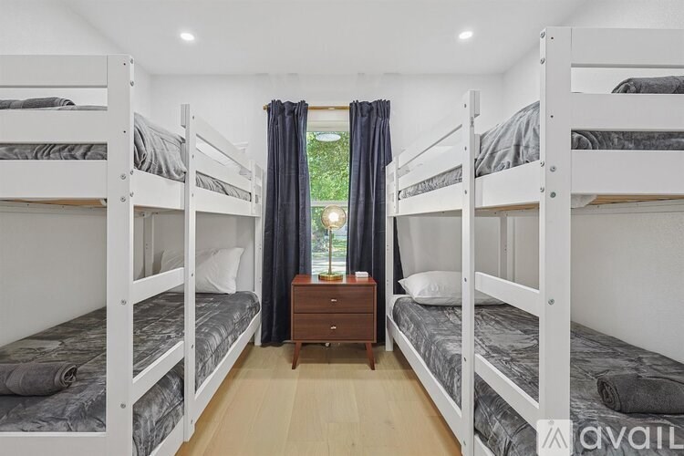 A room with white bunk beds and a wooden nightstand.