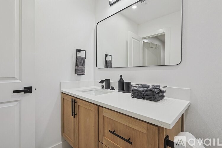 A bathroom with a white counter and wooden cabinets.