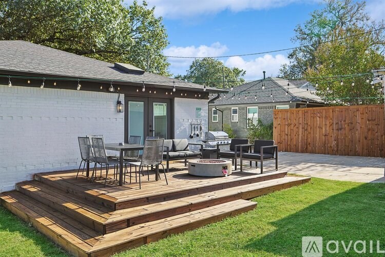 A wooden deck with chairs and a table is in front of a house.