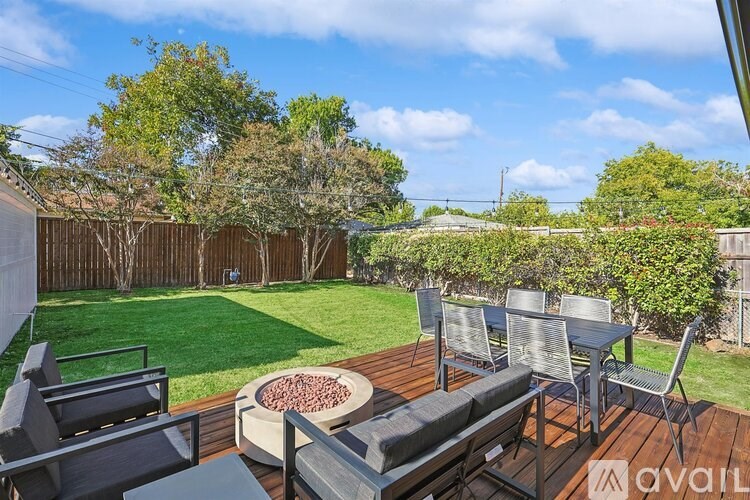 A backyard with a wooden deck and patio furniture.