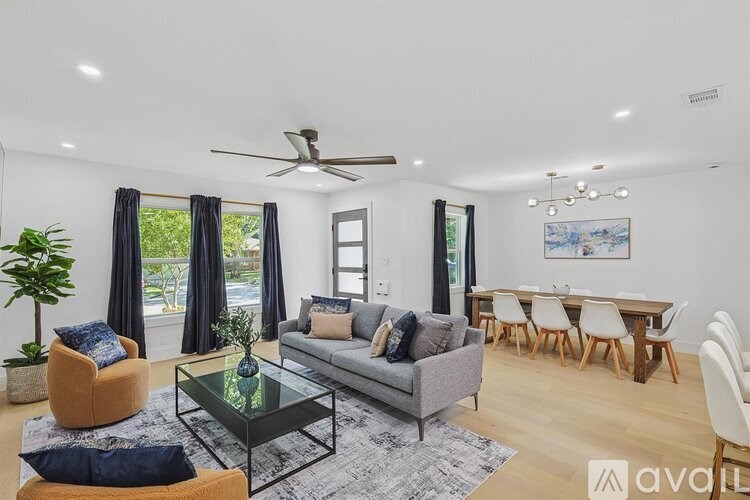 A living room with a grey couch, a glass coffee table, and a dining table with chairs.
