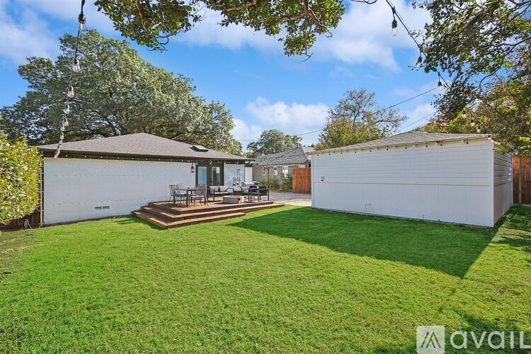 A backyard with a white fence and a green lawn.