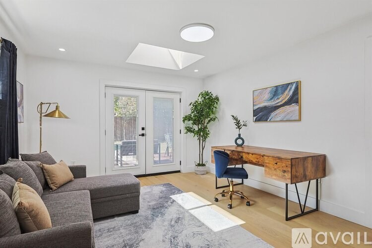 A living room with a grey couch, a wooden desk, and a blue chair.