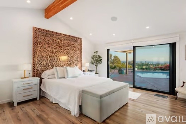 A bedroom with a large bed, a wooden headboard, and a sliding glass door.
