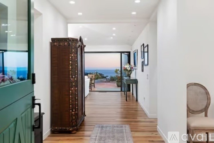 A long hallway with a chair and a cabinet on the right.