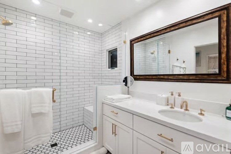 A bathroom with a white tile wall and a white sink.
