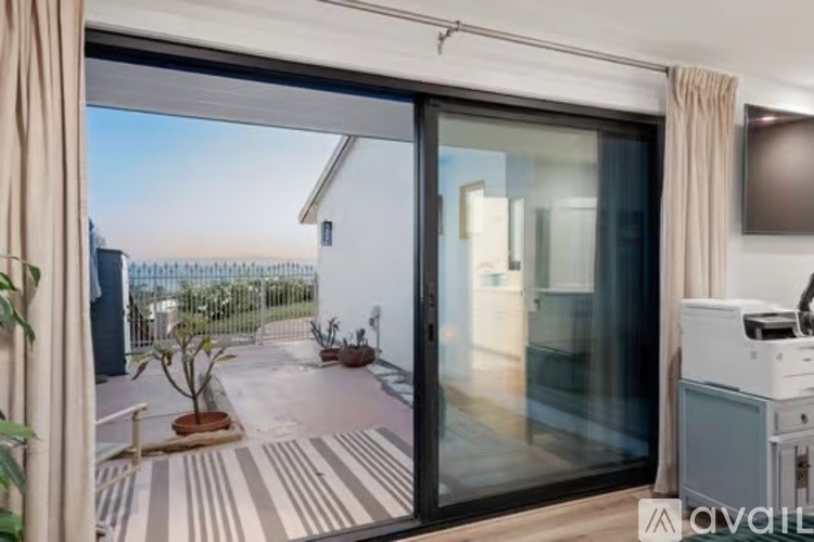 A balcony with a sliding glass door and a striped rug.
