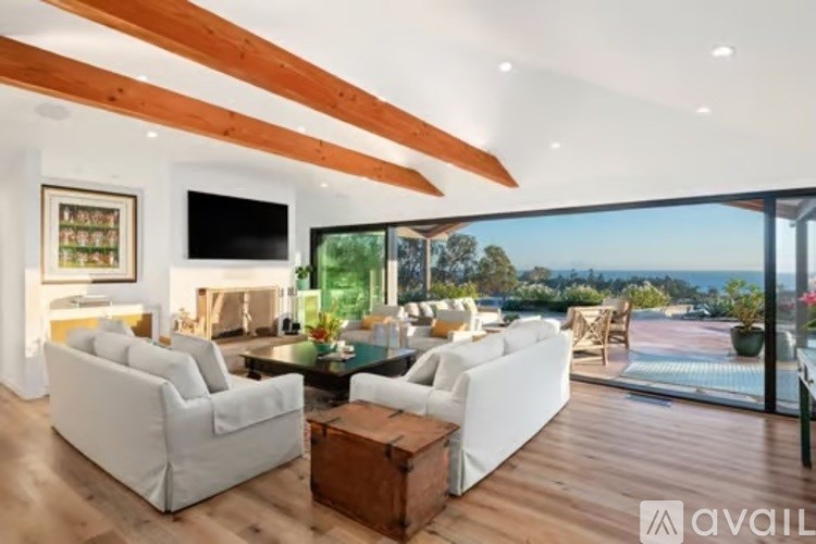 A modern living room with white furniture and a flat screen TV.