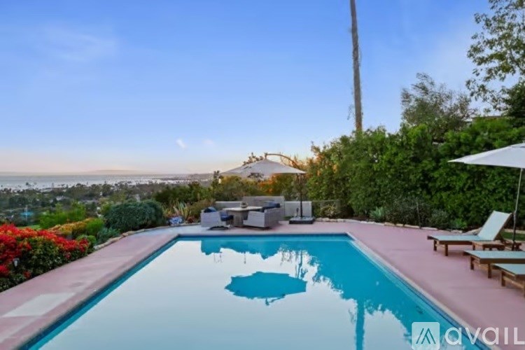 A pool with a reflection of the sky and a building in the distance.