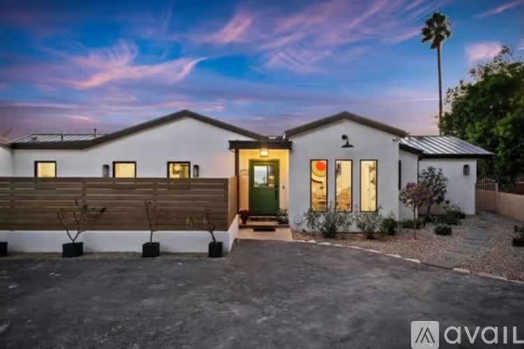 A modern house with a green door and windows is available for sale.