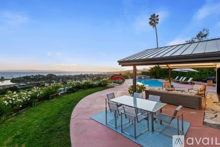 A patio with a table and chairs overlooking a body of water.