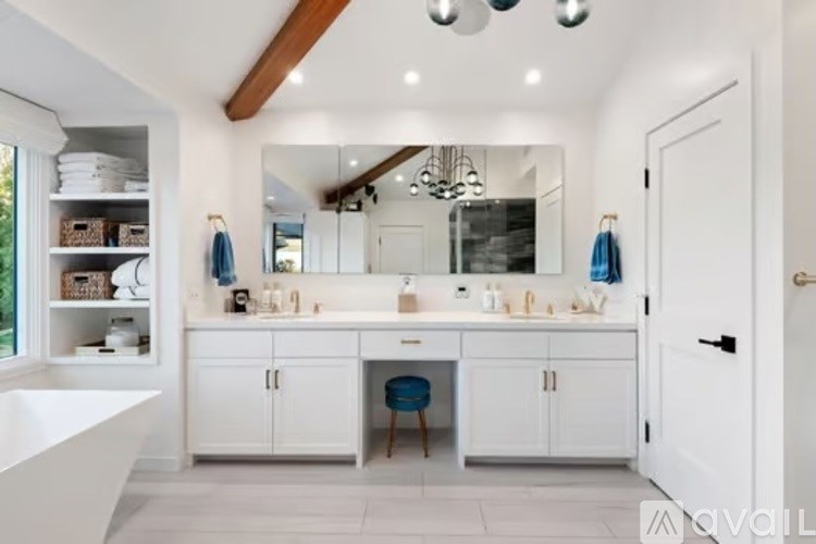 A modern bathroom with a large mirror, a sink, and a bathtub.