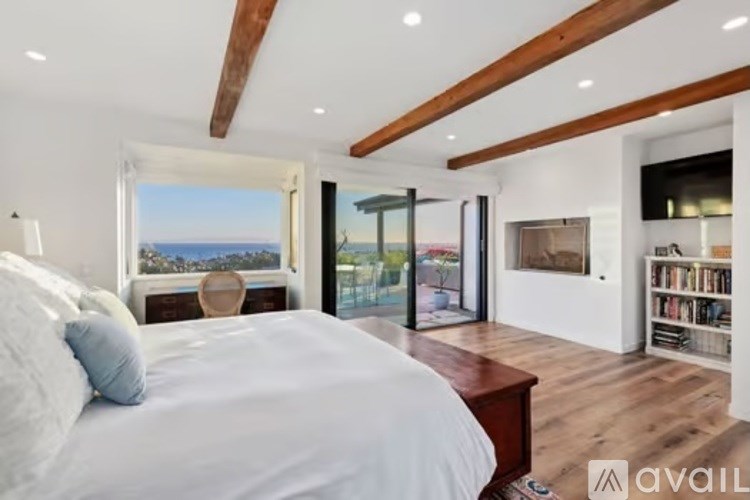 A bedroom with a large bed and a view of the ocean through a window.