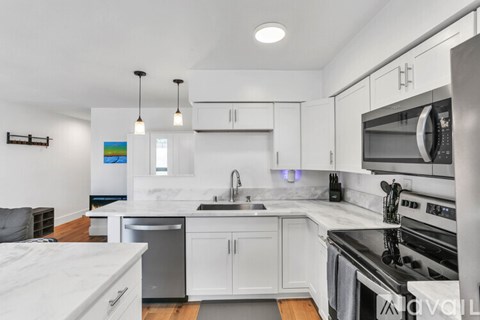 A modern kitchen with white cabinets and stainless steel appliances.