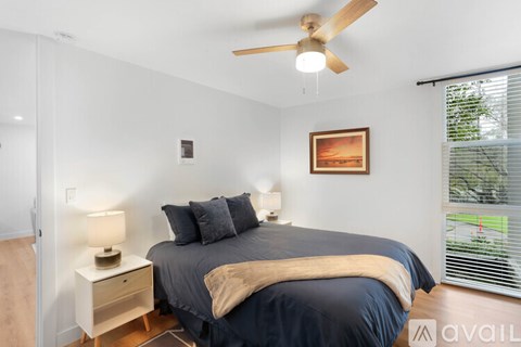 A bedroom with a bed, nightstand, and a ceiling fan.