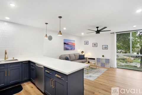 A modern kitchen with dark blue cabinets and a white countertop.