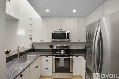 A modern kitchen with a stainless steel refrigerator and a microwave above the stove.
