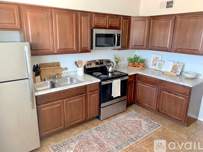 A kitchen with brown cabinets and a black refrigerator.
