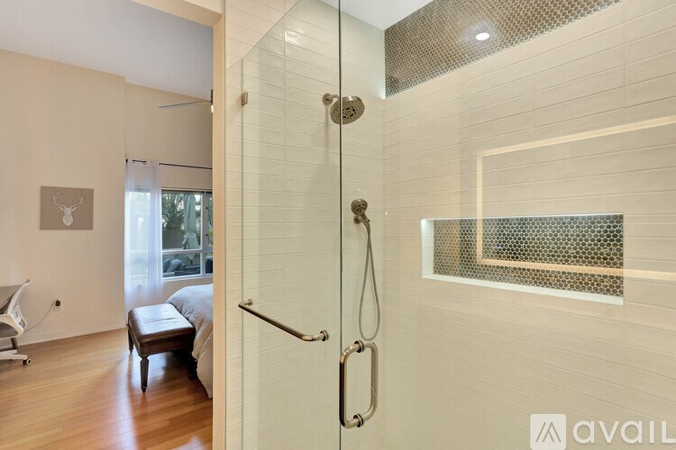 A bathroom with a glass shower door and a wooden floor.