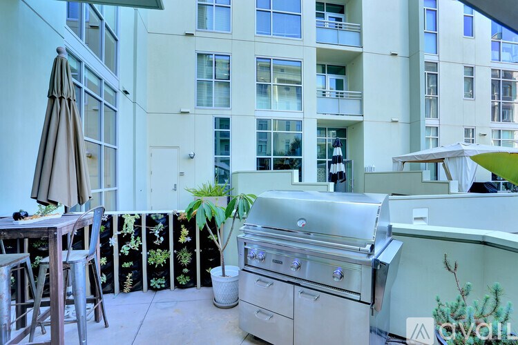 A patio with a grill and chairs is set up on a balcony.