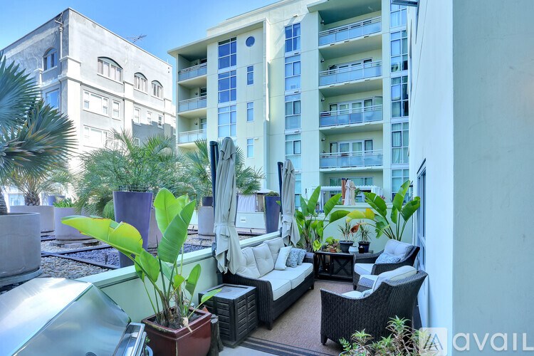 A balcony with a couch, chairs, and plants.