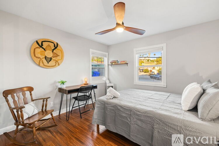 A kitchen with white cabinets and a white island with two brown barstools.