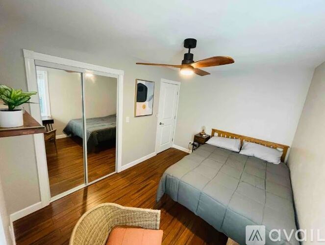 A bedroom with a bed, chair, and mirror.