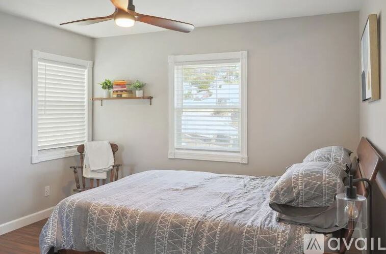 A bedroom with a bed, a ceiling fan, and a window with blinds.