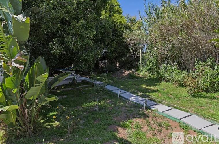 A garden with a white fence and greenery.