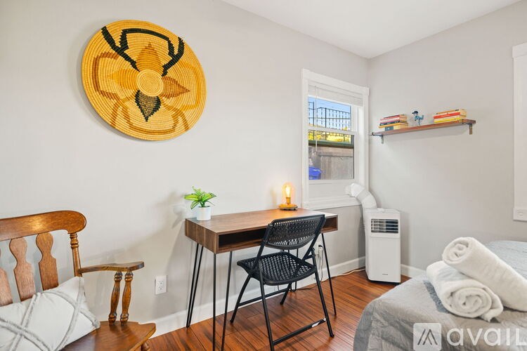 A room with a bed, a table with a plant and candles, and a wall hanging.