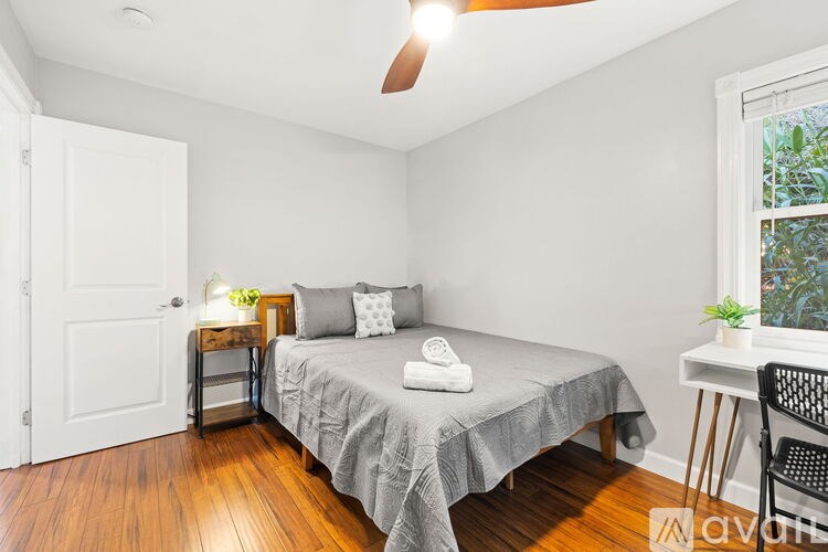 A bedroom with a bed, a chair, and a ceiling fan.