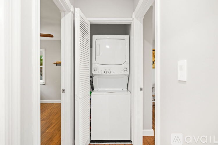 A white fridge is in a narrow hallway.