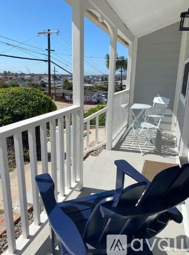 A balcony with a white railing and a blue chair.