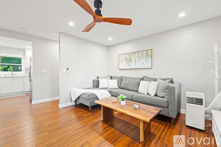 A living room with a grey couch, a wooden coffee table, and a ceiling fan.
