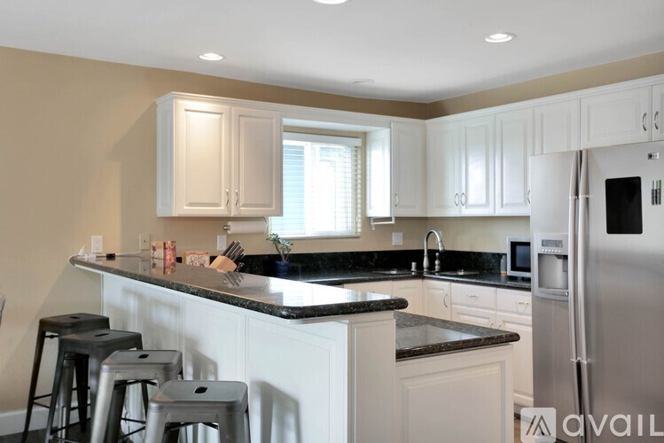 A kitchen with white cabinets and a black countertop.
