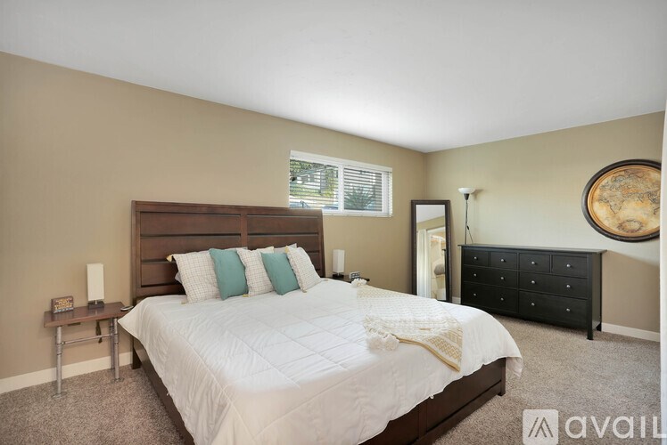 A bedroom with a large bed, a nightstand, and a dresser.