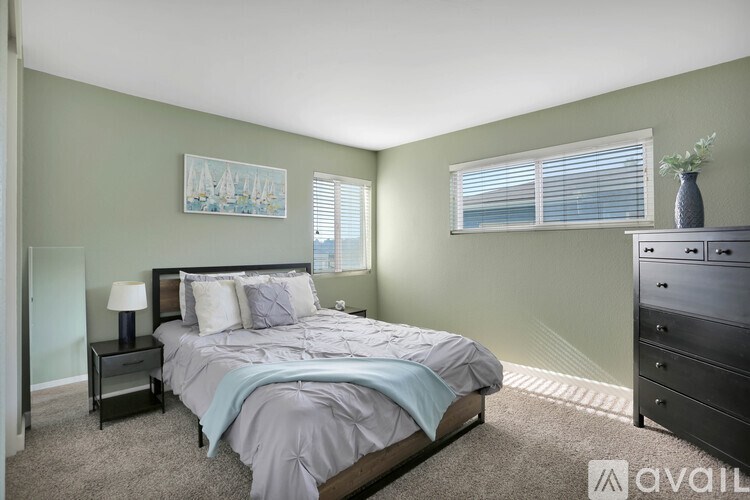 A bedroom with a bed, nightstand, and a painting on the wall.