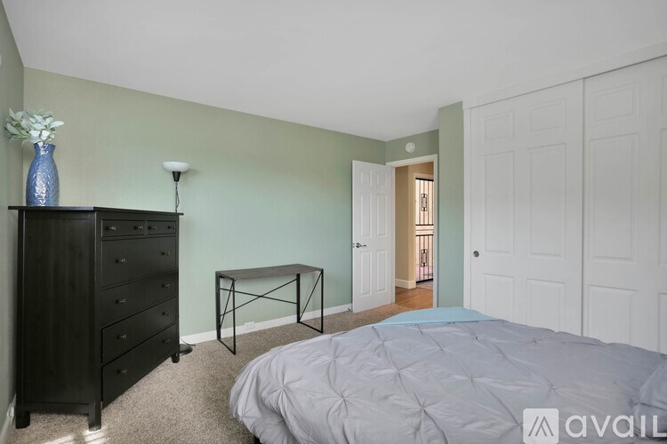A bedroom with a bed, dresser, and a table with a vase on it.