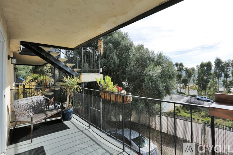 A balcony with a chair and a table with a potted plant on it.