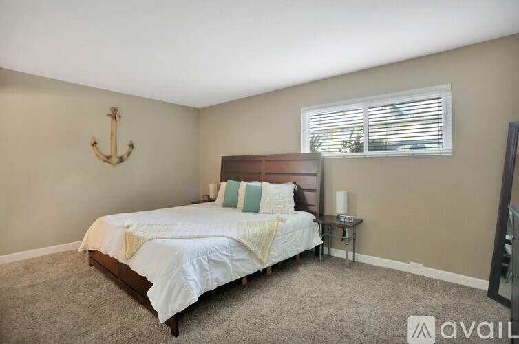 A bedroom with a bed, a small table, and a window with blinds.