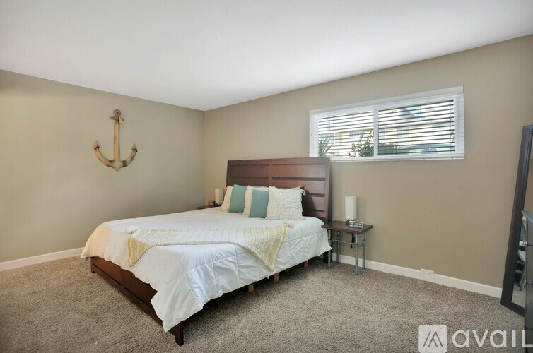 A bedroom with a bed, a small table, and a window with blinds.