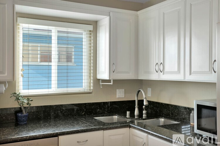 A kitchen with white cabinets and a black countertop.