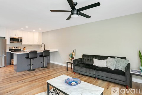 A modern living room with a black couch and a ceiling fan.