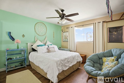 A bedroom with a bed, a chair, and a dream catcher on the wall.
