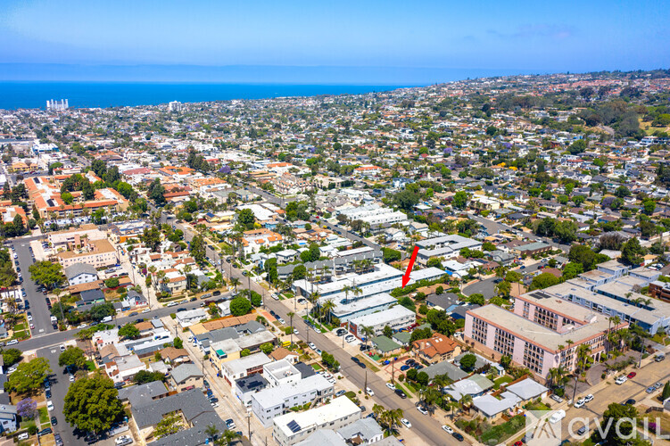 A bird's eye view of a city with buildings, roads, and a red arrow pointing to a specific building.