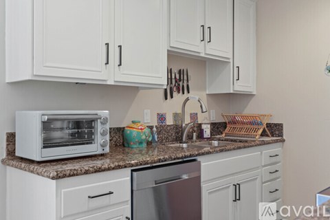 A kitchen with white cabinets and a granite countertop.