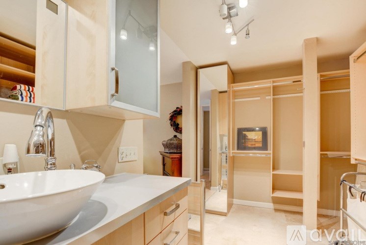 A bathroom with a white sink and wooden cabinets.