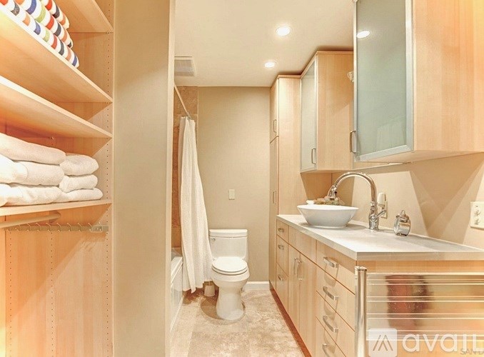 A bathroom with a toilet, sink, and towel shelf.